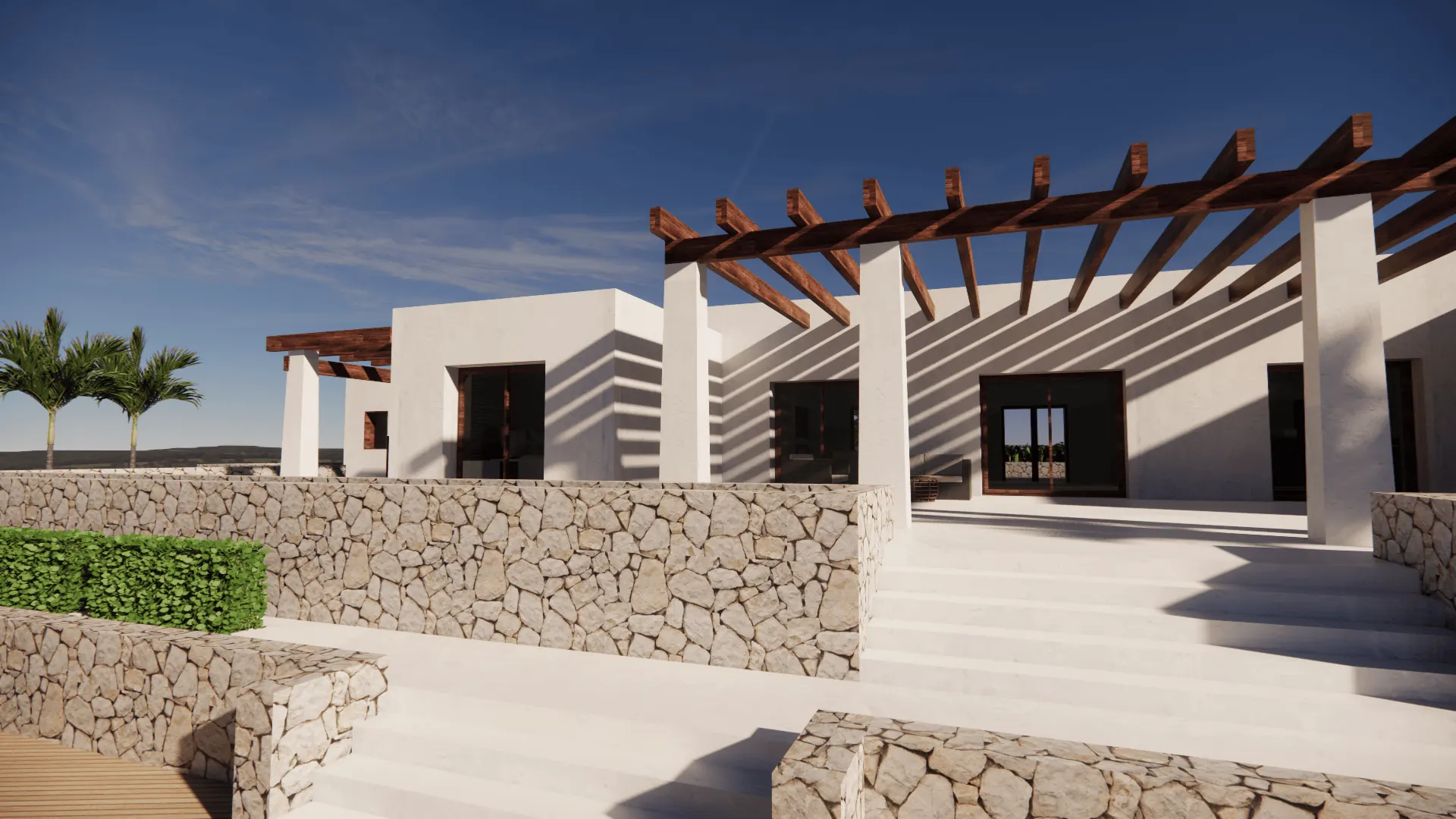La pérgola recorre la fachada y raya el encalado con sus sombras a lo largo del día. Los bancales de piedra seca resuelven el desnivel entre la casa y el jardín.