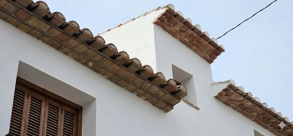 Detalle del alero: la teja árabe apoya sobre una hilada de ladrillo a sardinel, la solución tradicional del casco antiguo de Altea que la rehabilitación mantiene.